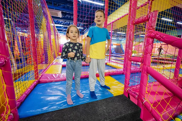Brother with sister playing at indoor play center playground.