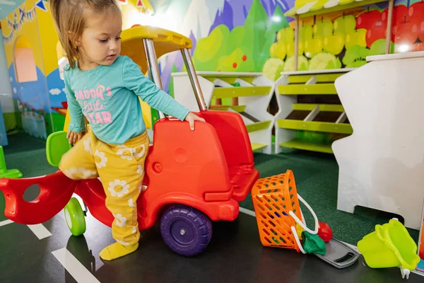 Kids playing at indoor play center playground , girl in toy car.