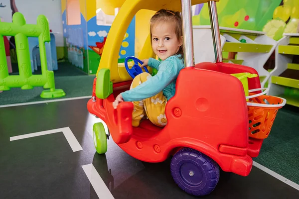Kids playing at indoor play center playground , girl in toy car.