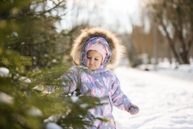 Baby girl wear child snowsuit on a sunny frosty winter day.
