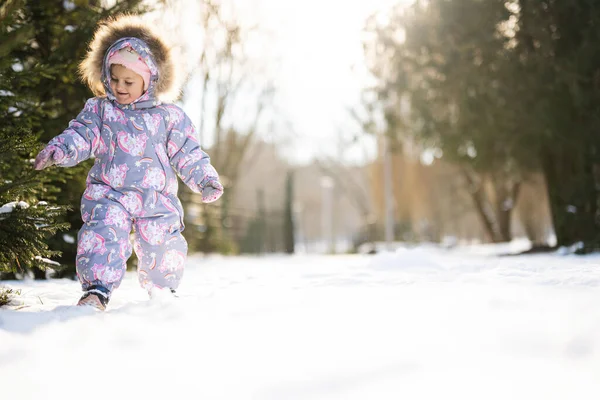 Baby girl wear child snowsuit on a sunny frosty winter day.