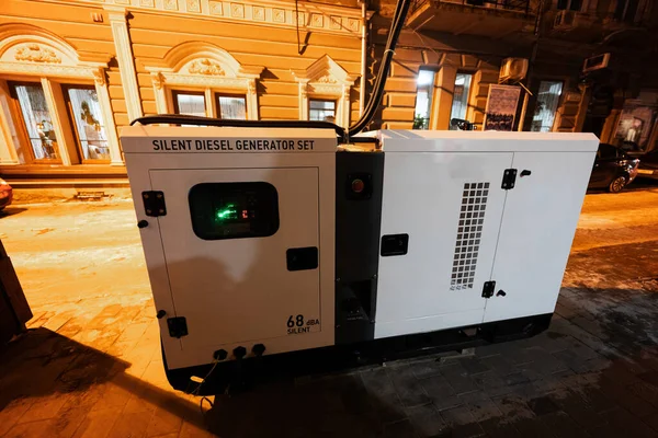 Large stationary diesel power three phase electric silent generator set in evening city.