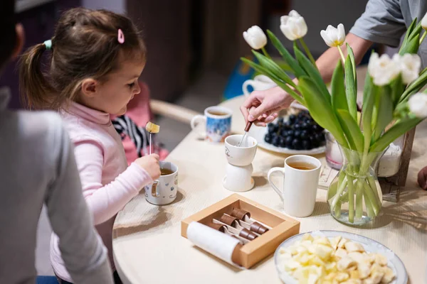 Children eat fruits and desserts, drink tea at home in the evening kitchen.
