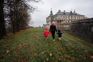 Back of mother holding hands two daughters visit Pidhirtsi Castle, Lviv region, Ukraine. Family tourist. 
