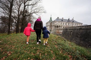 Back of mother holding hands two daughters visit Pidhirtsi Castle, Lviv region, Ukraine. Family tourist. 