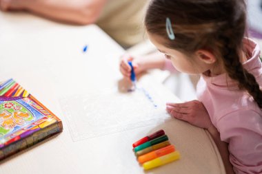 Girl decorating art with glitter decor pencil.