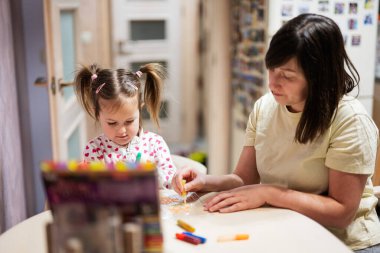 Mother and daughter decorating art with glitter decor.