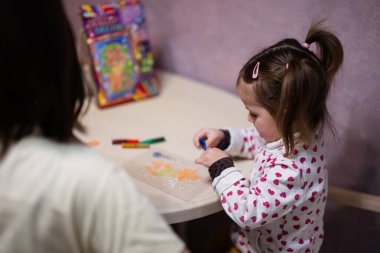 Mother and daughter decorating art with glitter decor.