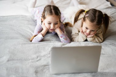 Two girls sisters watching on laptop. Technology and home concept.