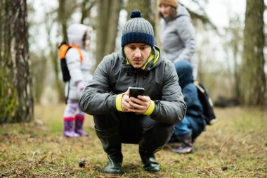 Man sat down to look at the phone in the forest with surprised face.