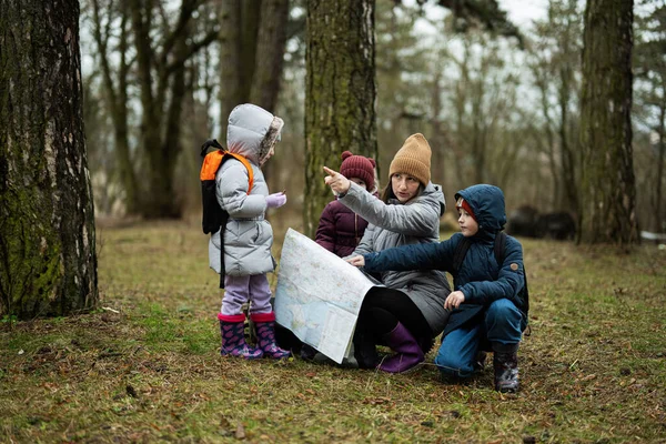 Mother and children with map in the forest.