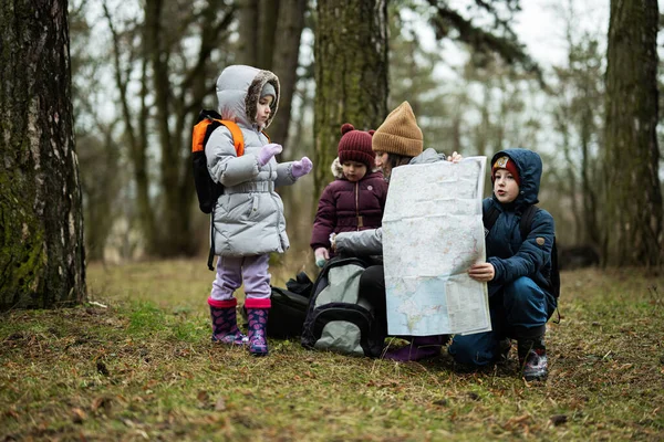 Mother and children with map in the forest.
