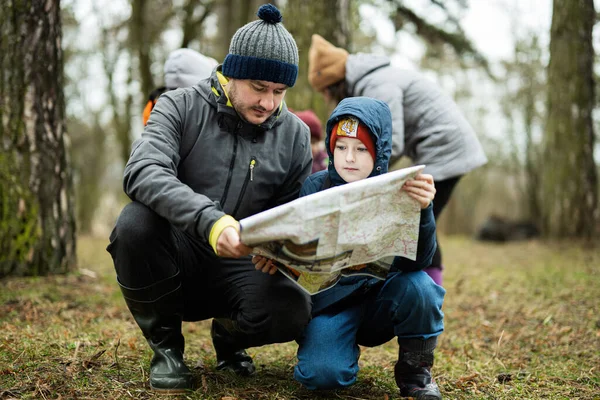 Father with son looking at map in the forest.