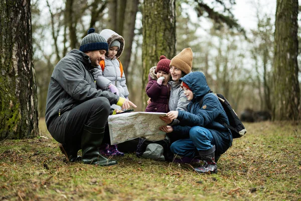 Family and kids with map in the forest.