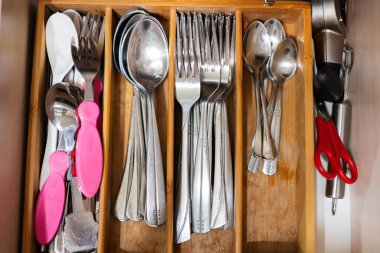 Clean and silver spoons, forks at kitchen drawer with cutlery set. Flat lay view of organizer tray with simple kit of utensils in open storage box.
