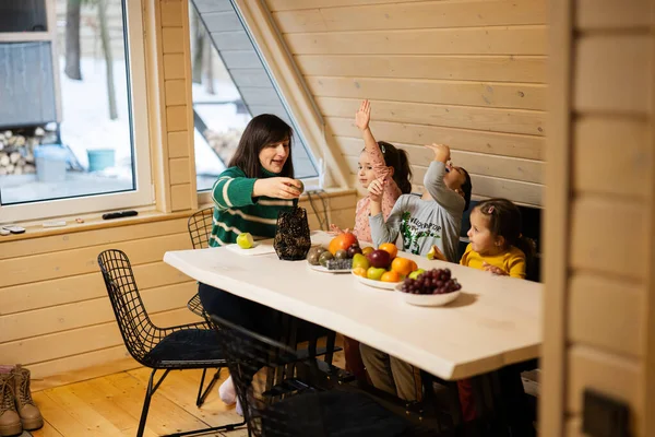 stock image Mother with three children eat fruits in wooden country house on weekend.