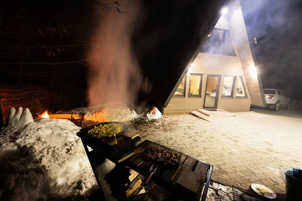 Wood fired barbecue against triangle country house at night.