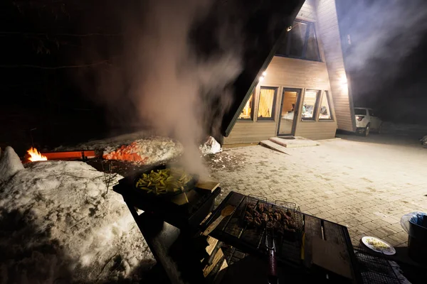 Wood fired barbecue against triangle country house at night.