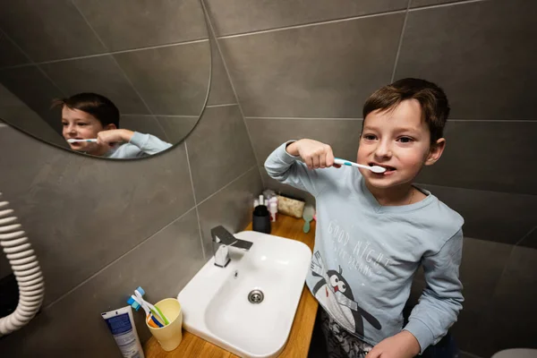 Boy brush teeth in mirror at bathroom.