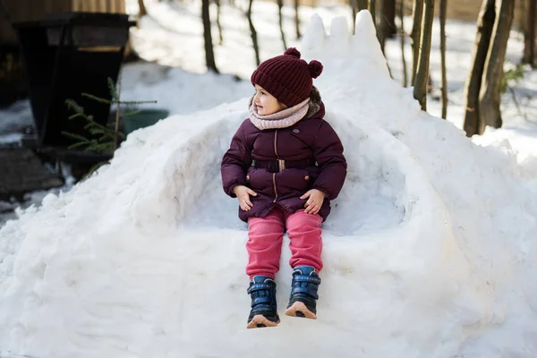 Κοριτσάκι Κάθεται Ένα Αυτοσχέδιο Θρόνο Φτιαγμένο Από Χιόνι — Φωτογραφία Αρχείου