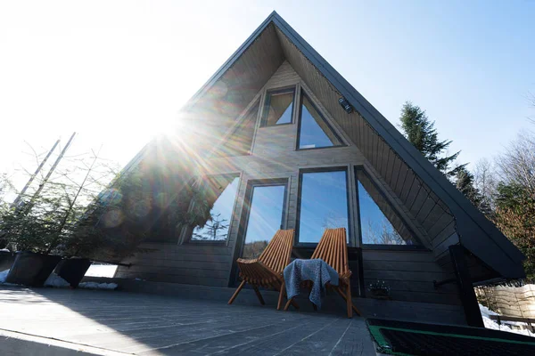 Stock image Sunbeam terrace of wooden triangle country tiny cabin house in mountains and two chairs. 