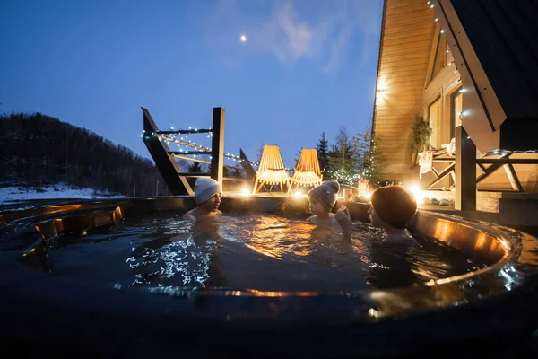 stock image Kids enjoying bathing in wooden barrel hot tub in the terrace of the cottage. Scandinavian bathtub with a fireplace to burn wood and heat water.