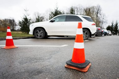 Trafik turuncu konileri park arabaları boyunca bir caddede duruyor..