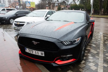 Ivano-Frankivsk, Ukrayna - Mart 2023: 777 plakalı siyah ve kırmızı Ford Mustang.