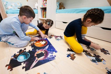 Children connecting jigsaw puzzle pieces in a kids room on floor at home.  Fun family activity leisure. 