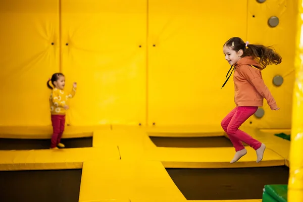 노란색 놀이터 공원에서 트램펄린 위에서 활동적 연예인들 사이에서 활동하는 자매들 — 스톡 사진
