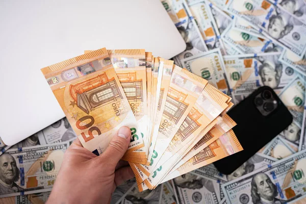 Man Hand Houden Euro Tegen Dollar Geld Laptop Telefoon Achtergrond — Stockfoto