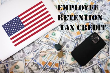 Employee retention tax credit concept. USA flag, dollar money with keys, laptop and phone background. clipart