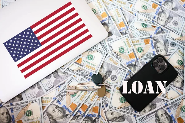 Loan concept. USA flag, dollar money with keys, laptop and phone background.