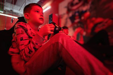 İki erkek oyuncu kırmızı oyun odasında oyun konsolu oynuyorlar..