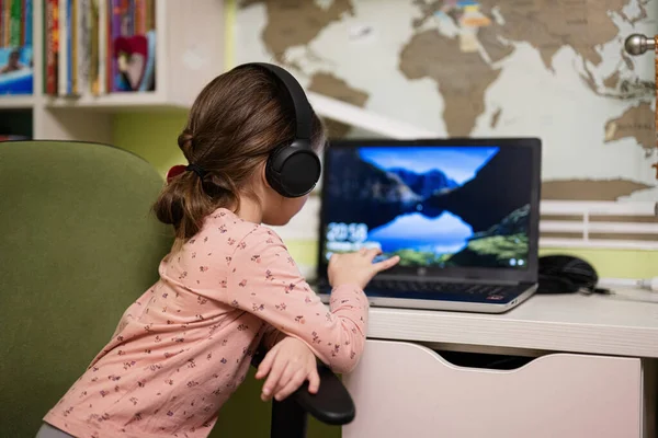 stock image Happy girl wearing headphones using laptop for learning from home, enjoys her remote education, having online lesson with school teacher. 