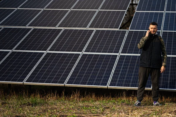Man with mobile phone on the background of solar panels.  Eco energy.