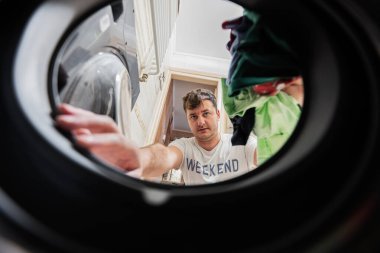 Man view from washing machine inside. Male does laundry daily routine. 