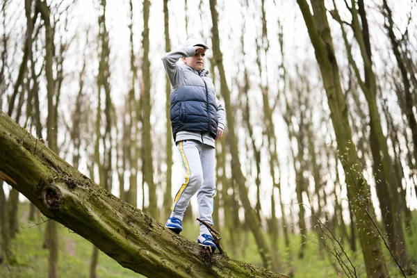 stock image Boy climbed a felled tree in spring forest. Happy childhood moments.