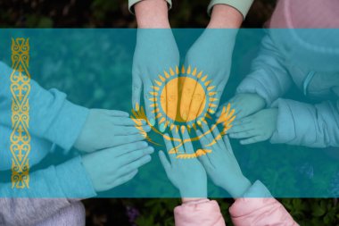 Kazakistan bayrağının arka planındaki çocukların elleri. Kazakistan vatanseverliği ve birlik kavramı.