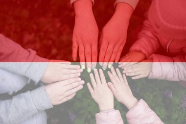 Endonezya bayrağının arka planındaki çocukların elleri. Endonezya vatanseverliği ve birlik kavramı.