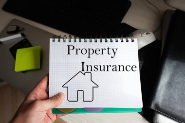 Not defterindeki emlak sigortası sözcüğü adamı masaüstüne karşı tutuyor.