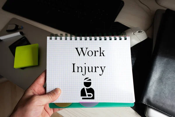 Work injury word on notebook holding man against desktop.