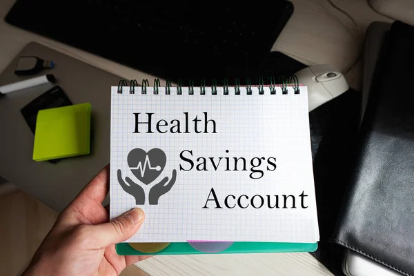 Health savings account word on notebook holding man against desktop.