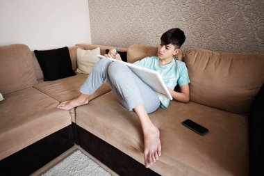 Genç bir erkek evdeki oturma odasında tuvale resim çiziyor. Hobi ve eğlence konsepti.