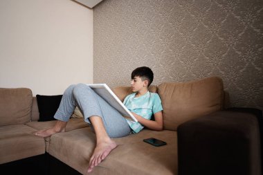 Genç bir erkek evdeki oturma odasında tuvale resim çiziyor. Hobi ve eğlence konsepti.