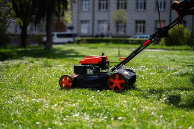 Şehir parkında çim biçme makinesi kullanan kamu hizmetleri bahçıvanı..