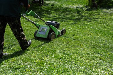 Şehir parkında çim biçme makinesi kullanan kamu hizmetleri bahçıvanı..