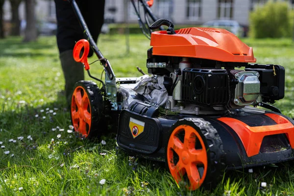 Stock image Communal services gardener worker man using lawn mower for grass cutting in city park.