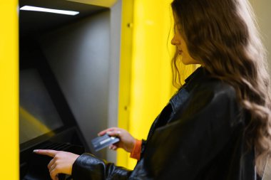 Genç esmer kız sarı ATM 'de kredi kartından para çekiyor..