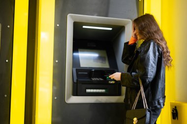 Olamaz, şifre koymayı unuttum. Genç, hayal kırıklığına uğramış esmer kız sarı ATM 'de kredi kartından para çekiyor..